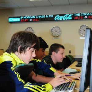 three boys working at a bloomberg terminal in the finance lab