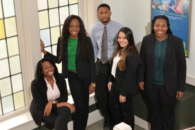 a group of student consultants wearing business attired pose in the stairway of Stephens Hall