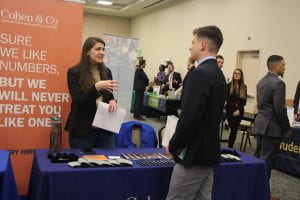 student talks to a recruiter at a table at the career fair