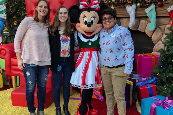 three people posing with Minney Mouse character at Disneyland