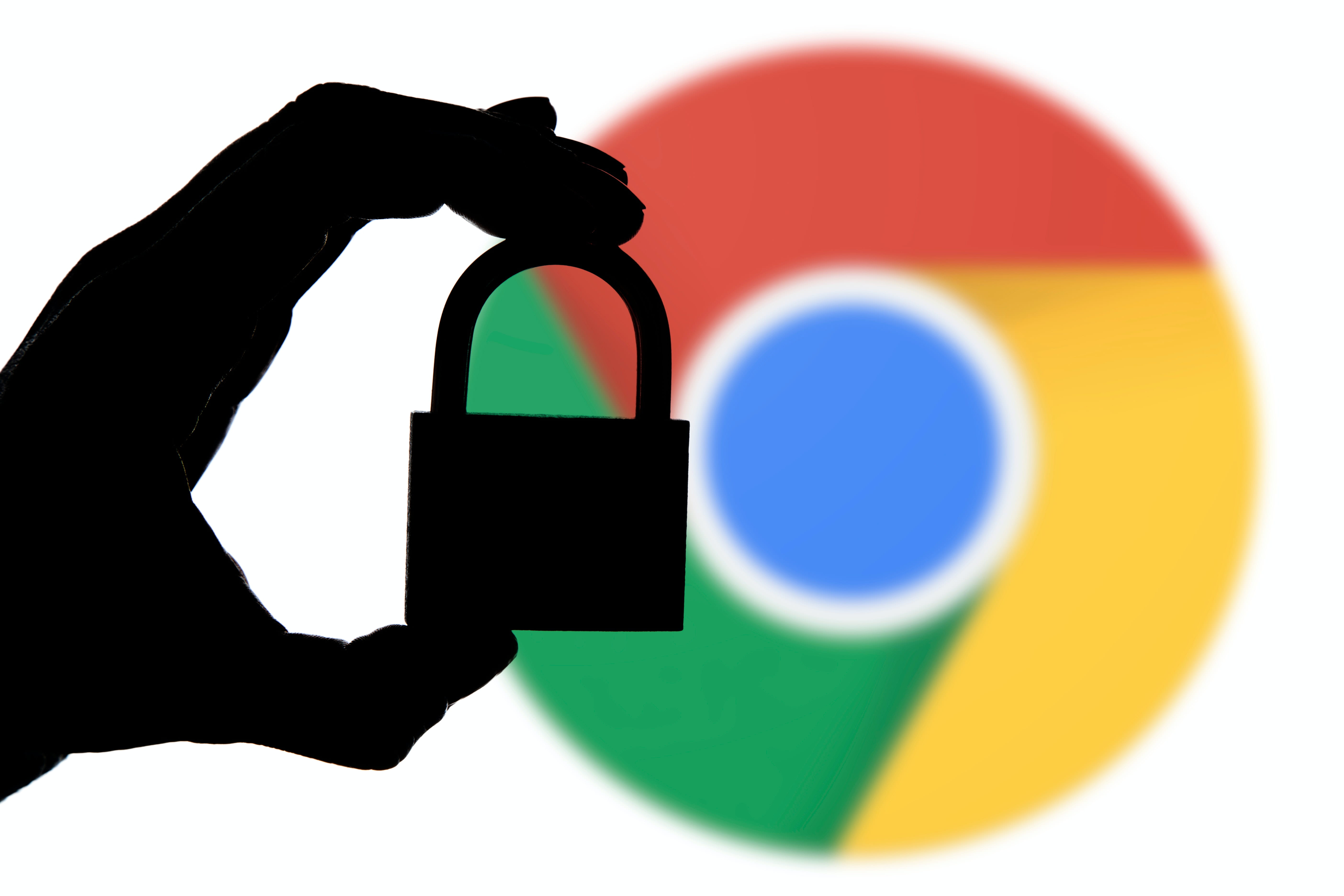 A hand holding a padlock in front of the Google Chrome icon