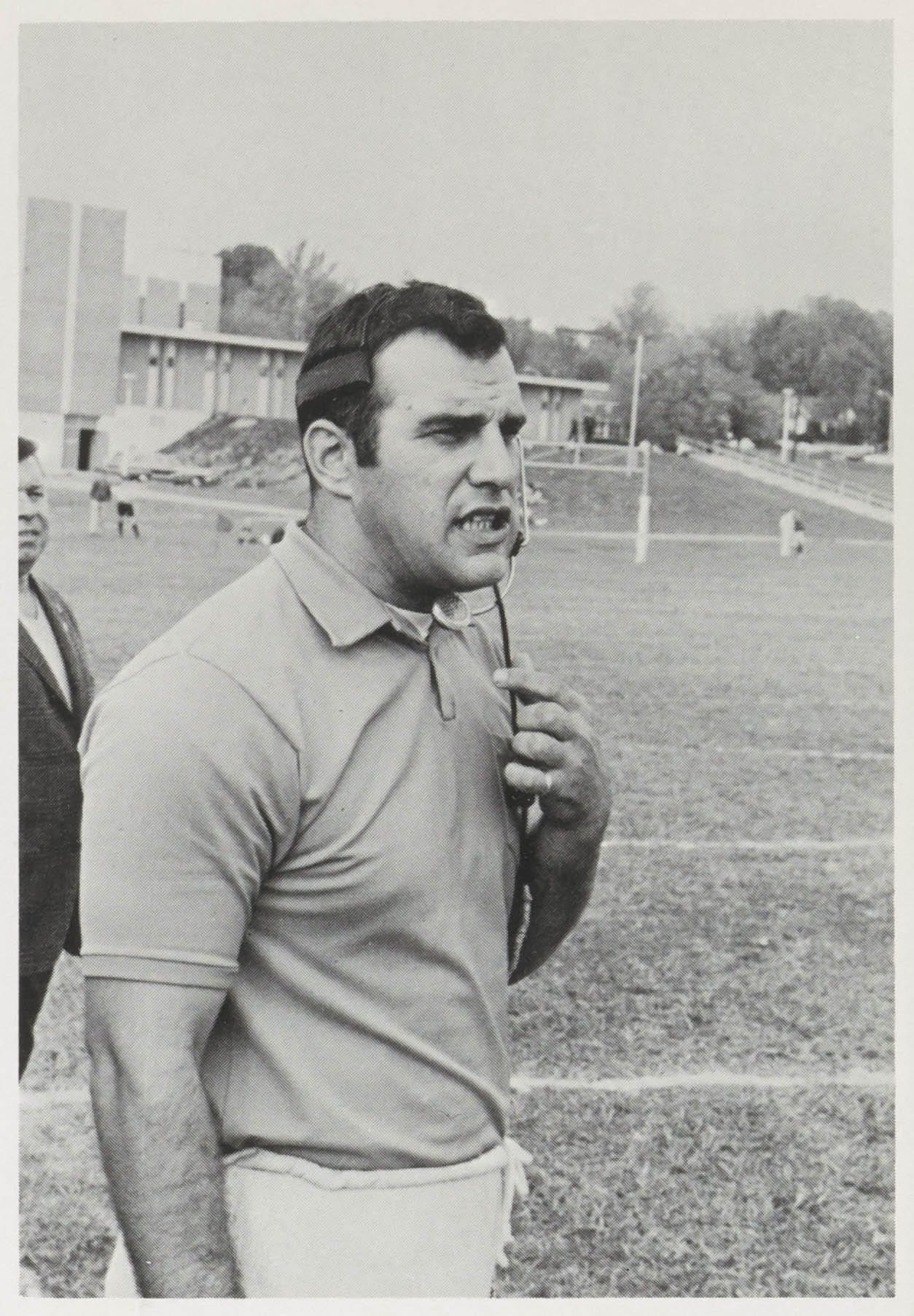 Photo of Carl Runk wearing a headset on a playing field. 