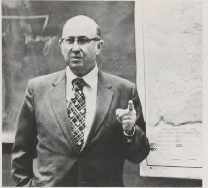 Blumberg standing in front of chalkboard teaching.