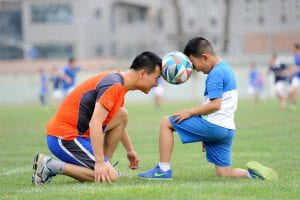 Child and coach playing soccer